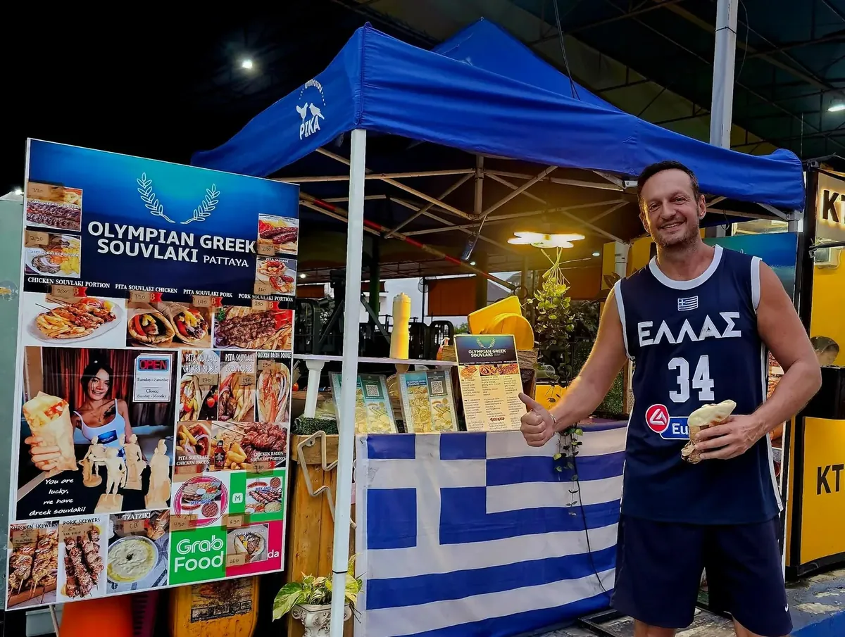 Yannis Pagiannidis, owner of Olympian Greek Souvlaki, holding a Greek flag at the Pattaya stall
